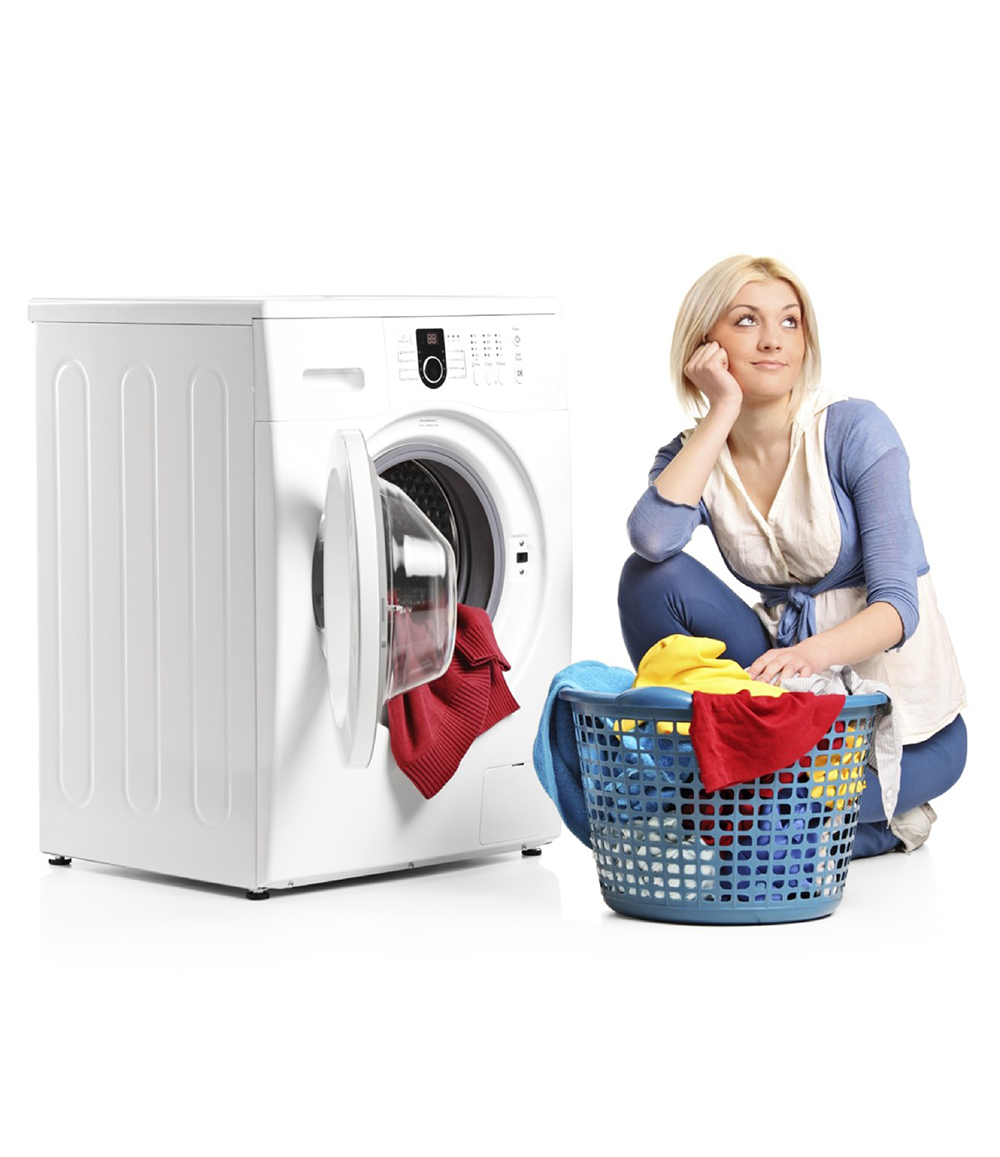 A lady sitting beside a washing machine with a basket of clothes